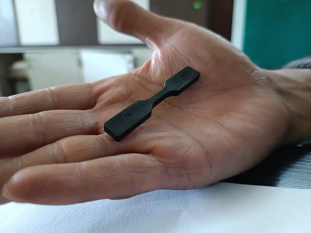man holds piece of recycled plastic made from chip packets by Indian social enterprise startup Ashy